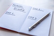 © leledaniele - Blank notebook page, with 'Travel diary' text, and pen beside it, on white wooden surface.