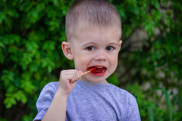 Wall Mural - Photo of a boy with a lollipop on a green background. Selective focus