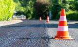 Construction cones marking part of road with a layer of fresh asphalt.