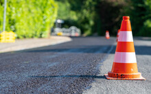 Construction Cones Marking Part Of Road With A Layer Of Fresh Asphalt.