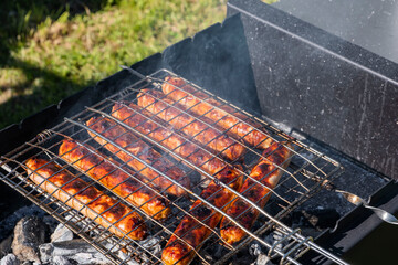 Grilled sausages on the charcoal grill, summer picnic in nature, barbecue bbq grill traditional German bratwurst hot dogs 