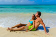 Two young beautiful people couple, sitting on the beach with a beach ball, interracial, black