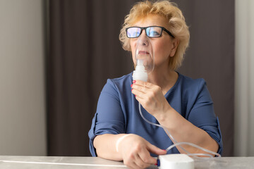 Sick elderly woman making inhalation, medicine is the best medicine. Ill senior woman wearing an oxygen mask and undergoing treatment. Senior woman with an inhaler