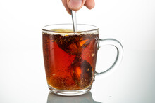 Stir With A Spoon A Piece Of Sugar In A Transparent Mug On A White Background