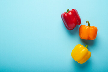 Wall Mural - Three fresh bright sweet peppers on a blue background. Top view, flat lay