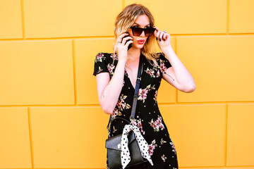 Wall Mural - Elegant fashionable woman posing near yellow wall