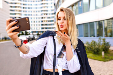 Wall Mural - Stylish young woman wearing trendy navy suit, posing near modern buildings