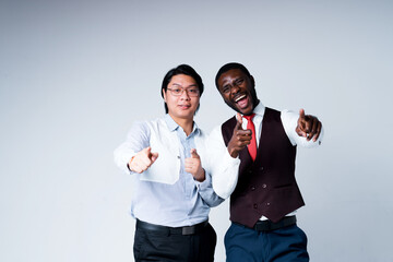 Wall Mural - African american and asian businessmen in suits smiling happily pointing fingers at camera