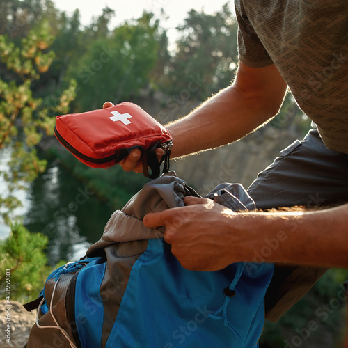 Young man taking out first aid kit from backpack