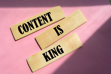 Wall Mural - word content is king on wooden block on pink background.