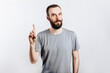 © Daria Lukoiko - Portrait of cheerful young handsome man smiling looking at camera pointing finger upwards on white background with space for advertising mock up