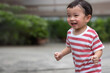 © TimmyTimTim - Portrait of an asian boy (toddler) running toward and smiling with happy and fun face while playing outdoor. A Child wear striped shirt in red and white color. Head and hair is wet by sweat.