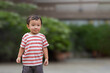 © TimmyTimTim - Portrait of s asian boy standing with smile and compress one's lips while playing outside in summer. Toddler child wear red and white striped shirt. Isolated in blurred background.