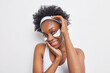 © wayhome.studio  - Portrait of beauty woman with healthy dark skinned well cared complexion smiles gently has relaxed face expression applies patches under eyes poses against white background. Afro American spa girl