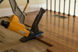 Nailing gun ready to staple sections of Brazilian Cherry tropical hardwood flooring in home renovation