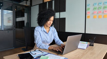 Young African American Focused Female Ceo Data Analyst Businesswoman Sitting At Desk Working Typing On Laptop Computer In Contemporary Corporation Office. Business Technologies Concept.