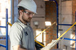 © puhimec - A handyman examines a drawing at a construction site.