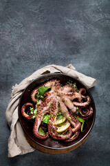 Wall Mural - Grilled octopus served with spices and lemon on gray background. Seafood concept.