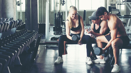 Trainer training exercise with man and woman at the gym for healthy care and body slim.  Fitness instructor exercising with his client people the fitness. Diet and Healthy sport Concept