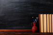 © Plutmaverick - Books, pens and pencils in a jug on the table. Against the background of the chalkboard. Copy space.