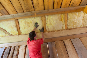 man installing glass wool insulation for new house construction