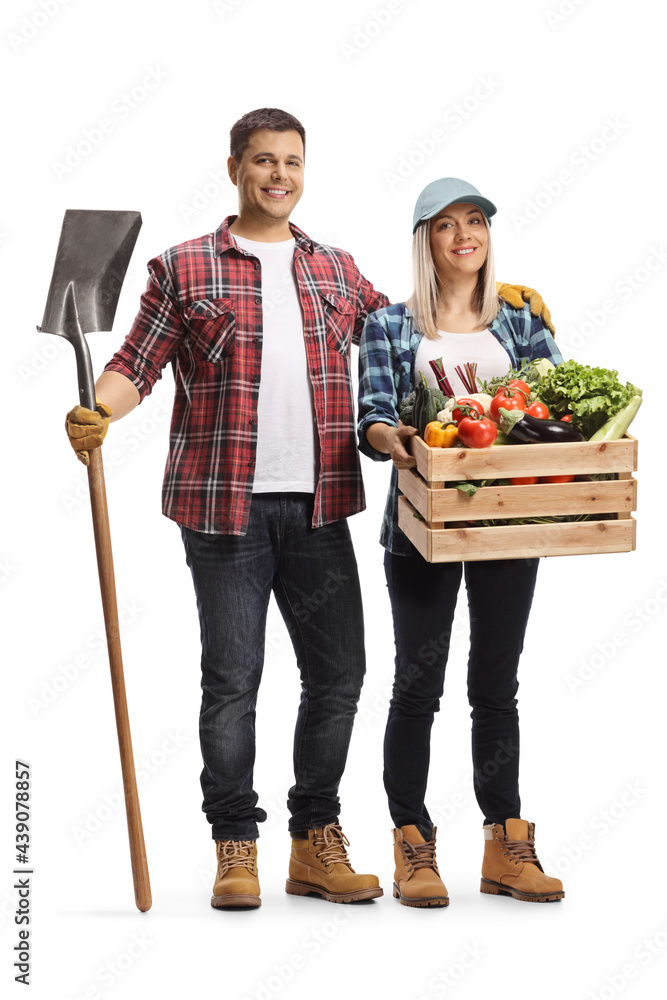 Full length portrait of a male farmer holding a shovel and a female ...