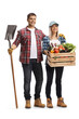 Full length portrait of a male farmer holding a shovel and a female farmer holding a crate with vegetables