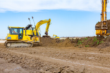 Two excavators and earthmover are leveling ground construction site