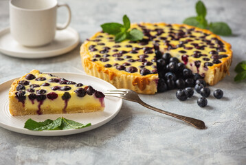 Homemade blueberry custard tart on light background.