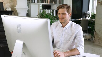 Sticker - Young man sitting at his desk in the office, working on computer.