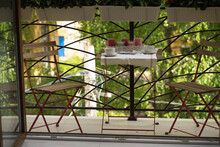 Balcony With Two Chairs, A Table And Red Flowers