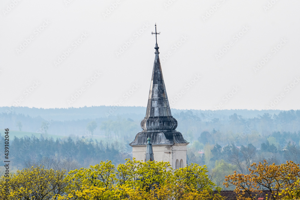 Wieża kościelna wśród kwitnących drzew. Symbol chrześcijaństwa - kościół z krzyżem - obrazy, fototapety, plakaty 