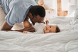 © Yakobchuk Olena - Multiracial father kissing his cute baby, while little child resting on the bed