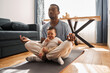 © Yakobchuk Olena - Man in casual clothes meditating with his son and sitting on lotus pose at home