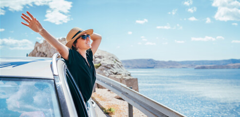 cheerful woman portrait enjoying the seaside road trip. dressed a black dress, straw hat and sunglla