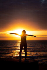 Wall Mural - a beautiful woman's silhouette with her arms outstretched standing in front of lake michigan water r