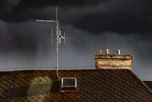 Dark Sky With Rain Clouds Over The Roof Of The House With An Antenna