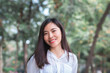 © thithawat - attractive adult business woman asian girl with happy and smile standing on walk way go to working between her office on morning under green forest.