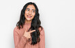 © Krakenimages.com - Hispanic teenager girl with dental braces wearing casual clothes cheerful with a smile of face pointing with hand and finger up to the side with happy and natural expression on face