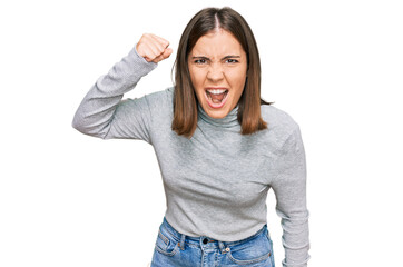 Poster - Young beautiful woman wearing casual turtleneck sweater angry and mad raising fist frustrated and furious while shouting with anger. rage and aggressive concept.