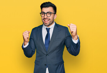 Wall Mural - Hispanic man with beard wearing business suit and tie screaming proud, celebrating victory and success very excited with raised arms