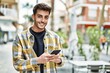 © Krakenimages.com - Handsome hispanic man smiling happy and confident at the city using smartphone