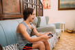 © Brastock Images - Young latin man with down syndrome playing video games at home.