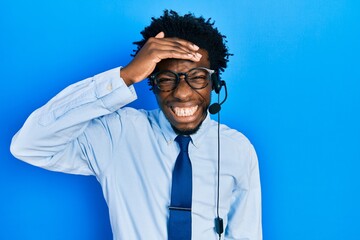 Poster - Young african american man wearing call center agent headset stressed and frustrated with hand on head, surprised and angry face