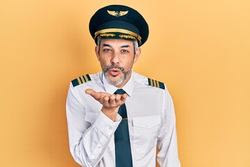 Sticker - Handsome middle age man with grey hair wearing airplane pilot uniform looking at the camera blowing a kiss with hand on air being lovely and sexy. love expression.