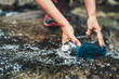 Close-up photo of female hands filling up a fresh cold mountain stream water into the plastic touristic bottle while water break on the tourist hiking route. Active people or water resources concept.