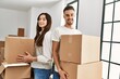 © Krakenimages.com - Young hispanic couple smiling happy holding cardboard boxes moving at new home.