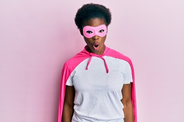 Canvas Print - Young african american girl wearing superhero mask and cape costume afraid and shocked with surprise expression, fear and excited face.