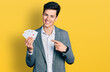 Young hispanic business man playing poker holding cards smiling happy pointing with hand and finger