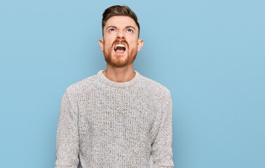 Wall Mural - Young redhead man wearing casual winter sweater angry and mad screaming frustrated and furious, shouting with anger. rage and aggressive concept.